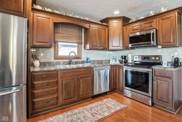 3784 Mansfield Dr, Brownsburg, IN 46112 - kitchen with appliances with stainless steel finishes, a sink, wood finished floors, tasteful backsplash, and recessed lighting