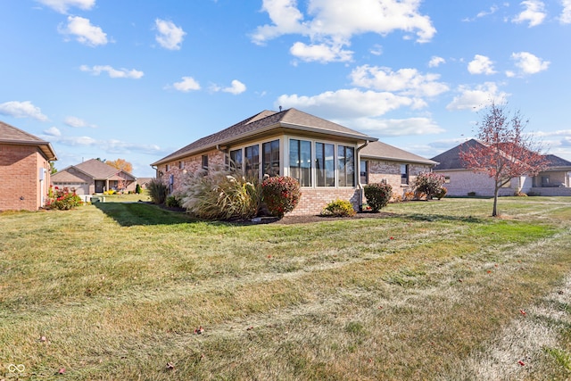 back of property with a yard and a sunroom