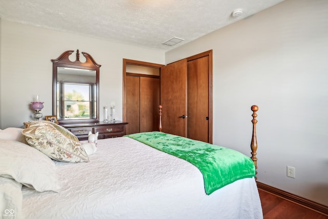 bedroom with a textured ceiling, a closet, and dark hardwood / wood-style flooring