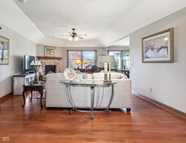 3784 Mansfield Dr, Brownsburg, IN 46112 - living room featuring a ceiling fan, baseboards, a brick fireplace, wood finished floors, and vaulted ceiling