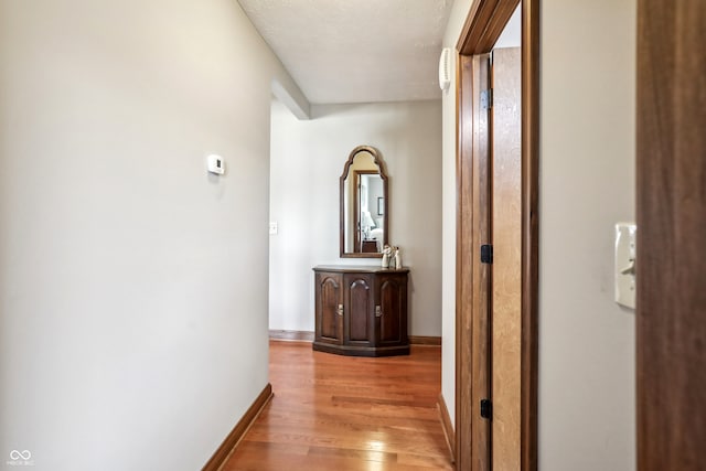 hallway featuring light hardwood / wood-style floors and a textured ceiling