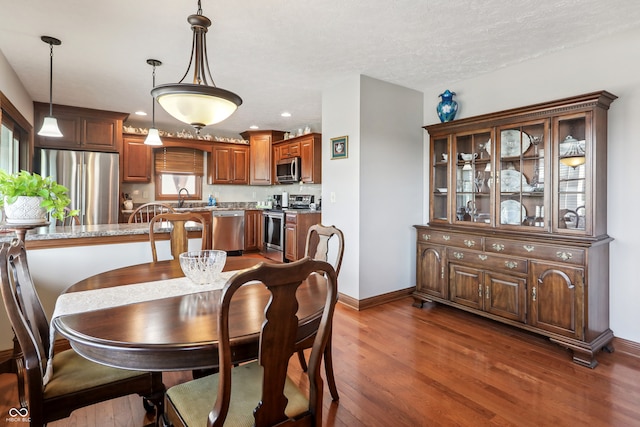 dining room featuring sink, dark wood-type flooring, and a textured ceiling