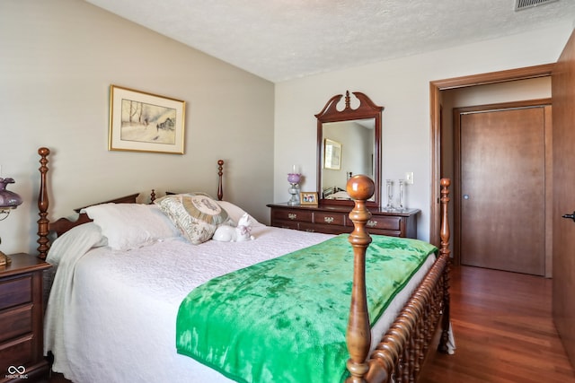 bedroom with a textured ceiling and dark hardwood / wood-style floors