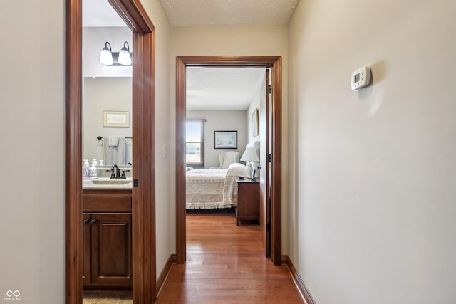 hallway featuring dark wood-type flooring, a textured ceiling, and sink