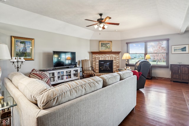 living room with dark wood-type flooring, ceiling fan, and a brick fireplace