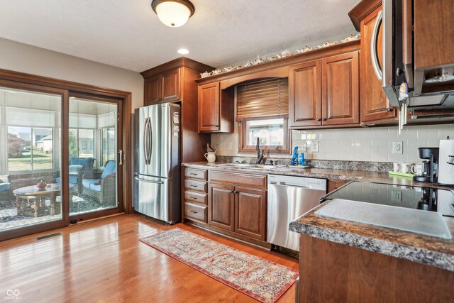 3784 Mansfield Dr, Brownsburg, IN 46112 - kitchen featuring stainless steel appliances, a sink, light wood finished floors, and brown cabinetry