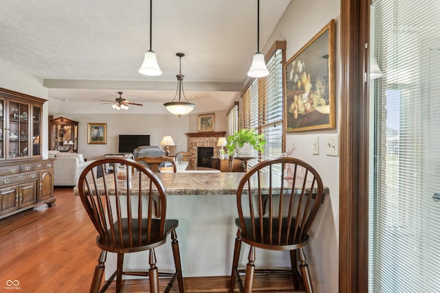 3784 Mansfield Dr, Brownsburg, IN 46112 - kitchen with a brick fireplace, a ceiling fan, glass insert cabinets, a peninsula, and a kitchen breakfast bar