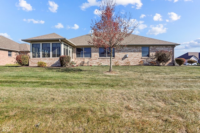 rear view of property featuring a yard and a sunroom