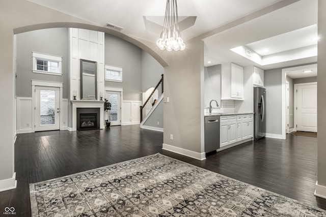 kitchen featuring white cabinets, stainless steel appliances, tasteful backsplash, and dark wood-type flooring