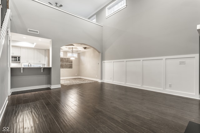 unfurnished living room with dark wood-type flooring, a high ceiling, and an inviting chandelier