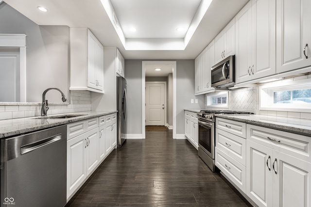 kitchen with white cabinets, stainless steel appliances, light stone countertops, and sink