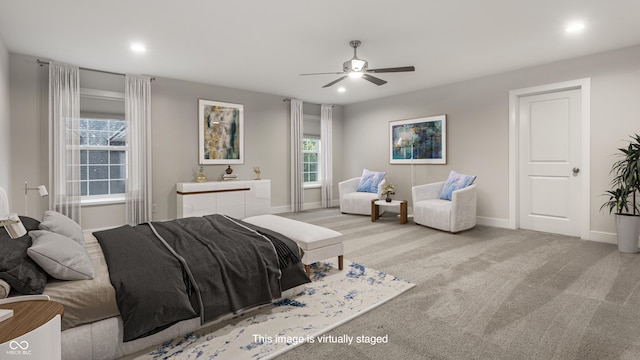 bedroom featuring multiple windows, light colored carpet, and ceiling fan