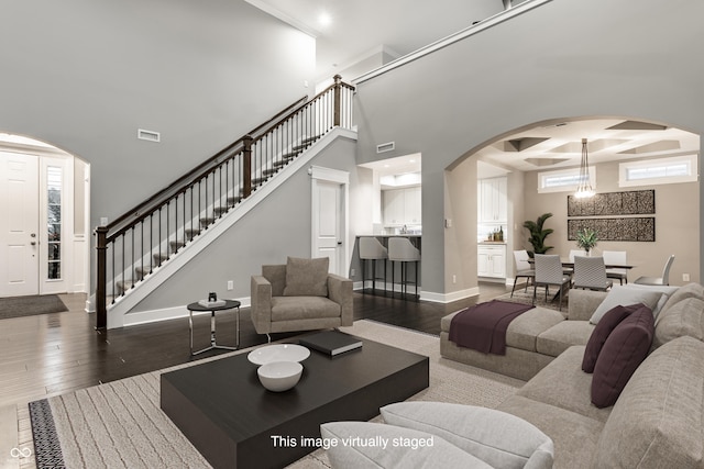 living room featuring a chandelier, dark wood-type flooring, and coffered ceiling