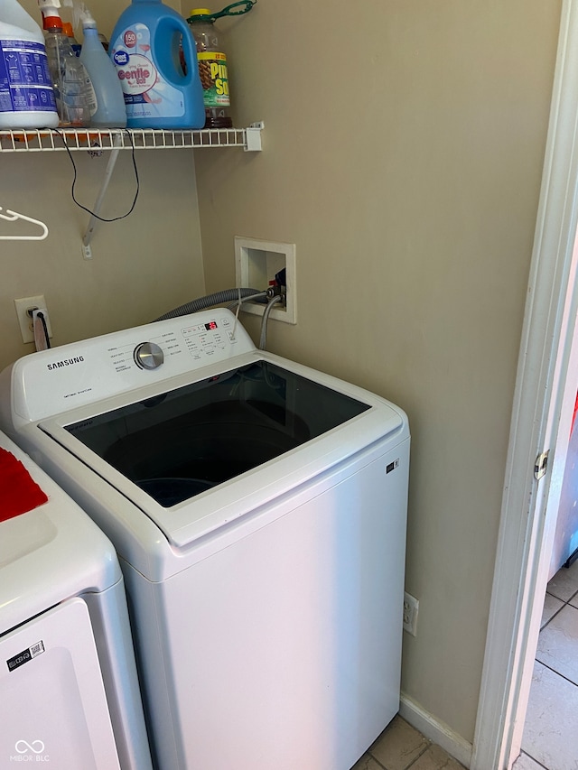 clothes washing area featuring washer and clothes dryer and light tile patterned floors