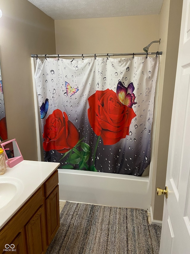 bathroom with shower / bath combo with shower curtain, a textured ceiling, and vanity