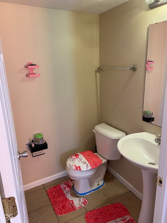 bathroom with toilet, a textured ceiling, and tile patterned floors