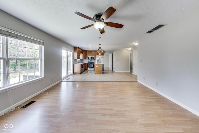 unfurnished living room with light hardwood / wood-style floors, a textured ceiling, and ceiling fan with notable chandelier