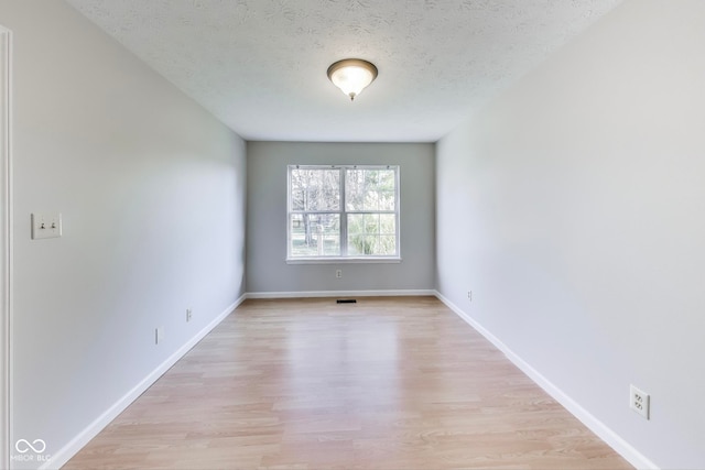 spare room with a textured ceiling and light hardwood / wood-style flooring