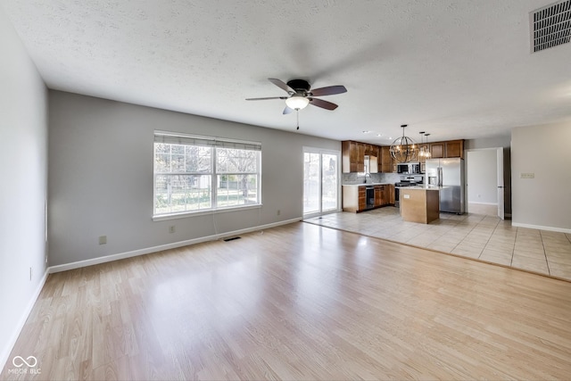 534 Austrian Way, Avon, IN 46123 - unfurnished living room featuring ceiling fan, light wood-type flooring, baseboards, a sink, and a textured ceiling