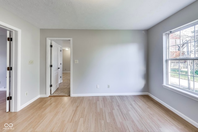 spare room featuring a textured ceiling and light hardwood / wood-style floors