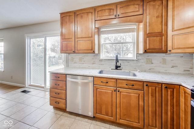 kitchen with decorative backsplash, light stone counters, light tile patterned floors, dishwasher, and sink