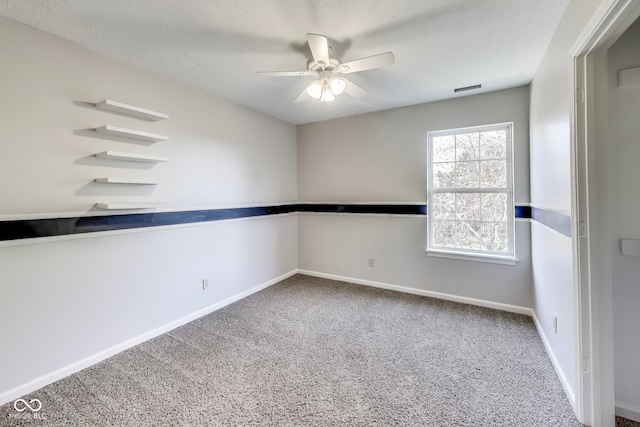 carpeted empty room with ceiling fan and a textured ceiling