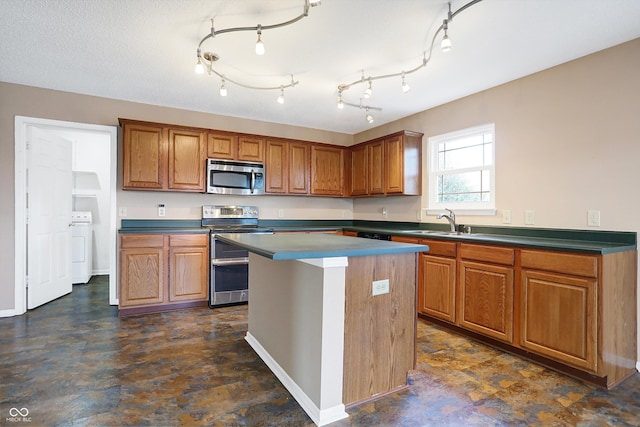 kitchen with sink, a textured ceiling, appliances with stainless steel finishes, a kitchen island, and washer / clothes dryer