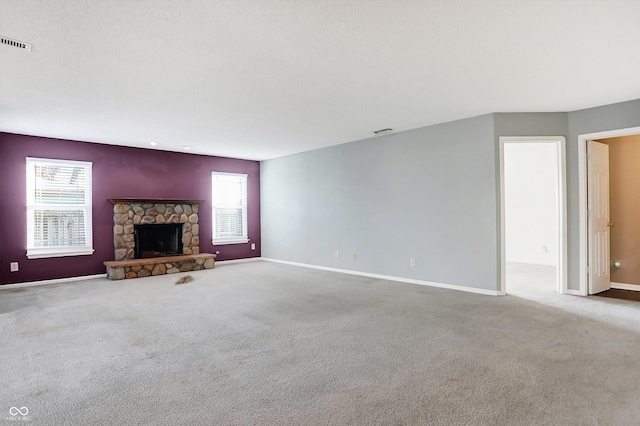 unfurnished living room featuring a fireplace, carpet, and plenty of natural light