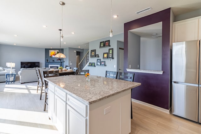 kitchen featuring a kitchen island, white cabinetry, a breakfast bar, and stainless steel fridge