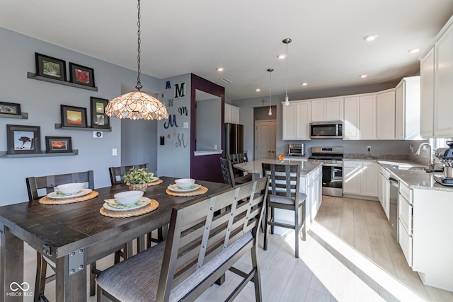 dining space with sink and light hardwood / wood-style flooring