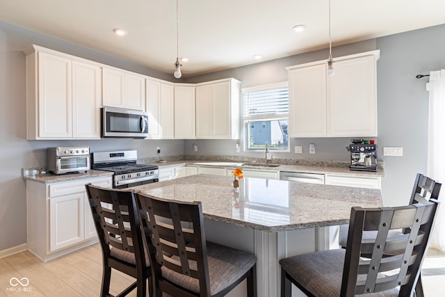 kitchen featuring pendant lighting, a center island, light stone countertops, and stainless steel appliances