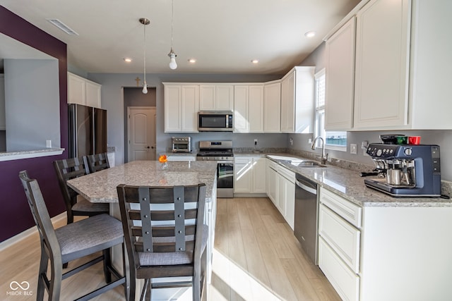 kitchen featuring light stone counters, pendant lighting, appliances with stainless steel finishes, and a center island