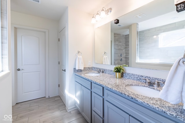 bathroom featuring tiled shower and vanity