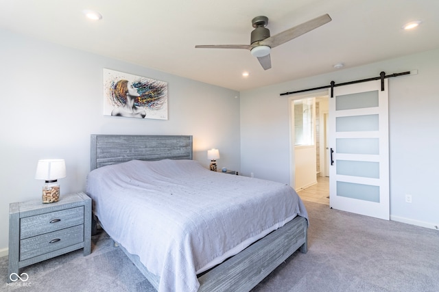 bedroom with light carpet, ensuite bath, ceiling fan, and a barn door