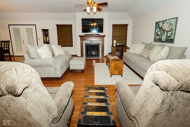 living room with hardwood / wood-style floors, ceiling fan, a fireplace, and lofted ceiling