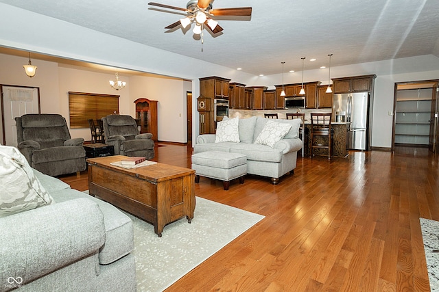 living room with dark wood-type flooring and ceiling fan with notable chandelier