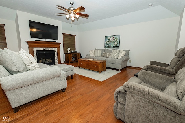 living room with hardwood / wood-style flooring, ceiling fan, and a fireplace