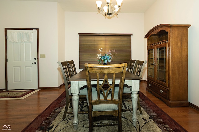 dining area with dark wood-type flooring and a notable chandelier