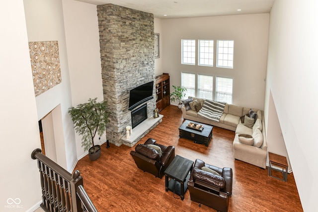 living room featuring a fireplace, a towering ceiling, and hardwood / wood-style floors