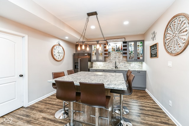 bar featuring decorative backsplash, sink, hanging light fixtures, gray cabinetry, and high end refrigerator