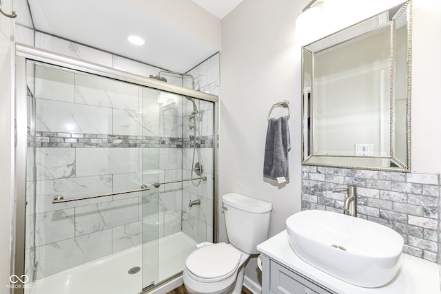 bathroom with a shower with shower door, vanity, decorative backsplash, and toilet