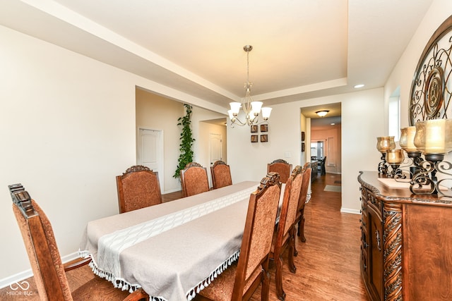 dining room featuring a notable chandelier, a tray ceiling, and hardwood / wood-style floors