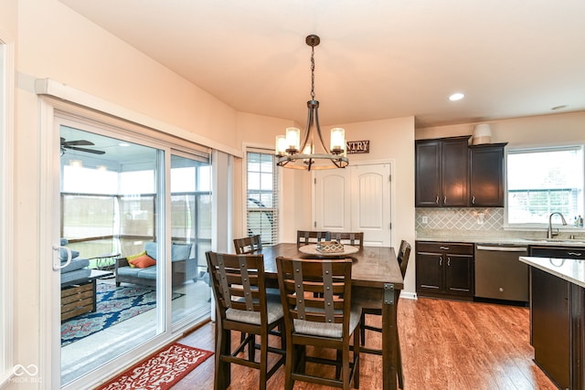 dining space with ceiling fan with notable chandelier, light hardwood / wood-style flooring, and sink