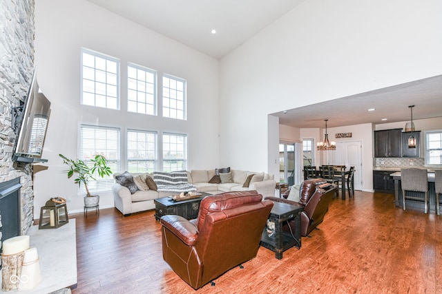 living room with hardwood / wood-style floors, a chandelier, a fireplace, and a high ceiling