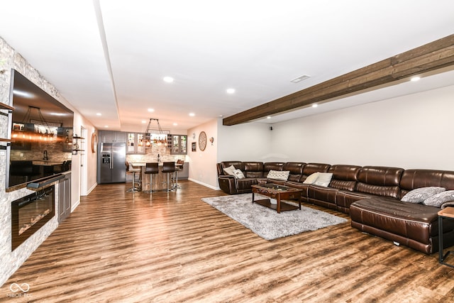 living room with a fireplace, bar area, beamed ceiling, and hardwood / wood-style flooring