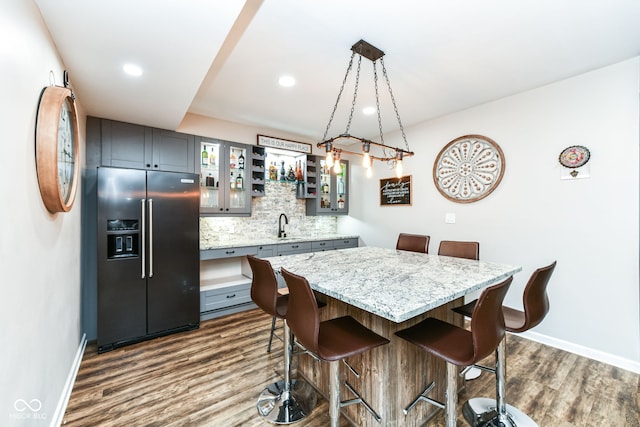 kitchen with a center island, high quality fridge, hanging light fixtures, gray cabinetry, and a breakfast bar area