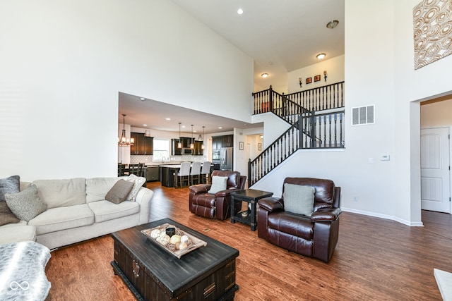 living room with a high ceiling, dark hardwood / wood-style flooring, and a notable chandelier