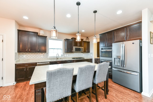 kitchen featuring sink, hanging light fixtures, stainless steel appliances, and a kitchen island