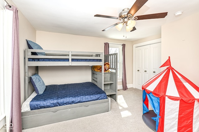 carpeted bedroom with ceiling fan and a closet