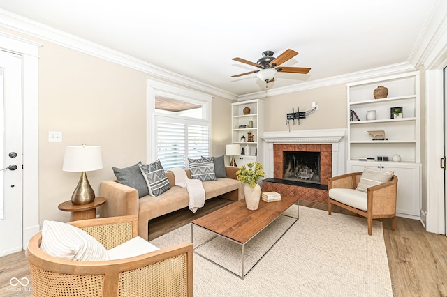 living room with a fireplace, crown molding, ceiling fan, and light hardwood / wood-style flooring